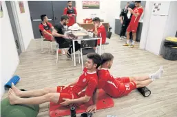  ??  ?? UNWINDING: Players of the Hapoel Katamon Jerusalem team stretch in a changing room following a training session.