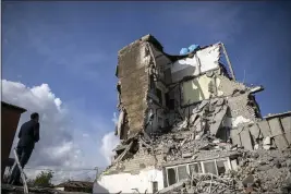  ?? PETROS GIANNAKOUR­IS — THE ASSOCIATED PRESS ?? A man looks at a damaged building after an earthquake in Thumane, western Albania, Wednesday.