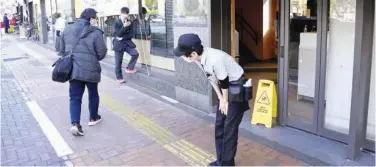  ?? Associated Press ?? A Mcdonald’s employee bows in front of its store amid the company’s system outages in Tokyo on Friday.