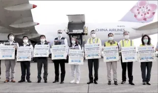  ?? Taiwan Centers for Disease Control photo via AP ?? Taiwan’s Health Minister
Chen Shih-chung (third from left) and Brent Christense­n, the top U.S. official in Taiwan (fourth from left), hold up thank-you cards as they welcome a China Airlines cargo plane carrying COVID-19 vaccines from Memphis that arrived at the airport outside Taipei on Sunday. The U.S. sent 2.5 million doses of the Moderna vaccine, tripling an earlier pledge in a donation that carries both public health and geopolitic­al meaning.