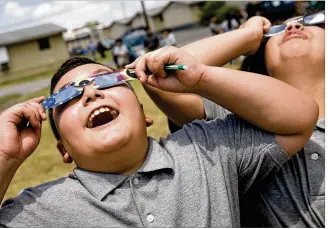  ?? JAY JANNER / AMERICAN-STATESMAN ?? Luis Collins, 11, and Joanna Castillo, 12, look at the solar eclipse Monday using protective eyewear from their vantage point at Burnet Middle School in Austin.