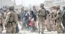  ?? VIA AP ?? Members of the British and U.S. military assist in the evacuation of people out of Kabul, Afghanista­n, on Friday.