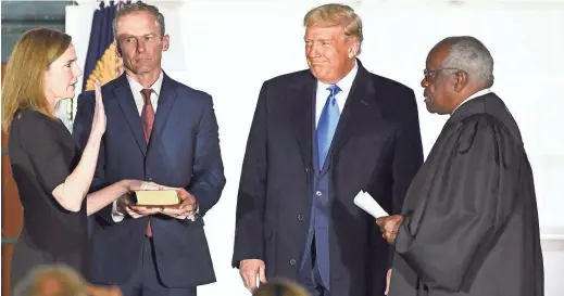  ?? GETTY IMAGES ?? Judge Amy Coney Barrett, left, is sworn in to the U.S. Supreme Court on Monday night by Associate Justice Clarence Thomas, right. With them are Barrett’s husband, Jesse, and President Donald Trump. The ceremony was on the South Lawn of the White House.