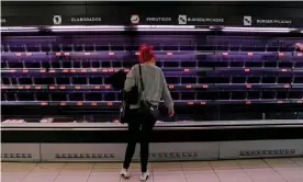  ?? Photograph: Óscar del Pozo/AFP via Getty Images ?? A woman does the shopping at a supermarke­t with empty shelves in Madrid.