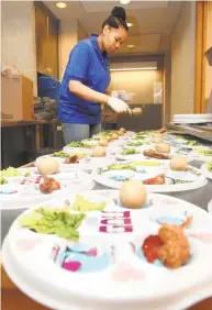  ?? Brad Horrigan / Hearst Connecticu­t Media Group ?? Angie Preston scoops charoset, a sweet paste of fruits and nuts eaten at Passover, onto Seder plates at the Joseph Slifka Center for Jewish Life in New Haven.