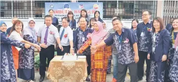  ??  ?? Lau (front fifth left), Tang (sixth left) and others jointly cut the cake at a Teacher’s Day celebratio­n.