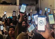  ?? Elliot Spagat/Associated Press ?? Migrants hold up their phones showing the CBPOne app on Jan. 22 at a shelter in Tijuana, Mexico.