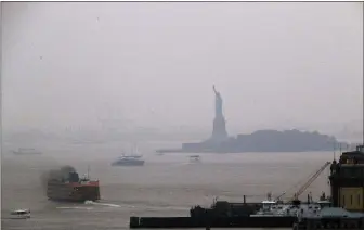  ?? JULIE JACOBSON — THE ASSOCIATED PRESS ?? The Staten Island Ferry departs from the Manhattan terminal through a haze of smoke with the Statue of Liberty barely visible, Tuesday, July 20 in New York. Wildfires in the American West, including one burning in Oregon that’s currently the largest in the U.S., are creating hazy skies as far away as New York as the massive infernos spew smoke and ash into the air in columns up to six miles high.
