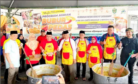  ?? ?? Hilmy (third left) leads the preparatio­n of ‘bubur pedas’ during the programme at Kampung Semariang Baru Phase 3.