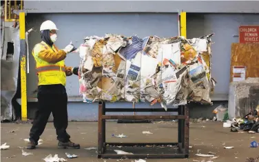  ?? Lea Suzuki / The Chronicle 2019 ?? Allen Maculangan removes plastic from a bale of paper at Recology’s recycling center in S.F. in 2019.
