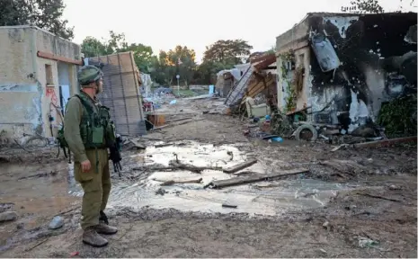  ?? Gil Cohen-Magen/AFP via Getty Images ?? Israeli troops search the scene of a Palestinia­n militant attack in the Israeli kibbutz of Kfar Aza on Oct. 11.