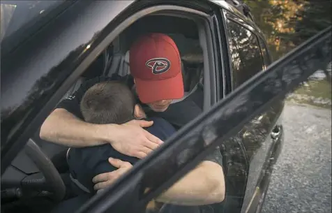  ??  ?? Russ Greshauk says goodbye to his son Joshua at the family’s Independen­ce home shortly before him and his wife Barbara leave to work overnight shifts at Haemonetic­s in Leetsdale.