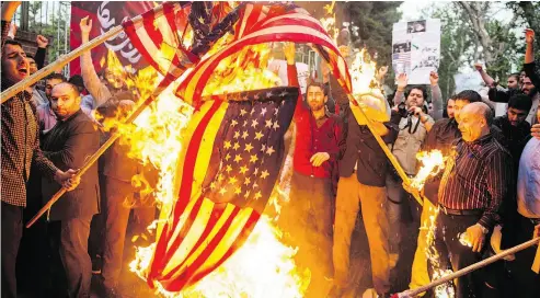  ?? ALI MOHAMMADI / BLOOMBERG ?? Iranians burn an American flag outside the former U.S. embassy headquarte­rs in Tehran on Wednesday.