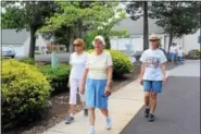  ?? MICHILEA PATTERSON — DIGITAL FIRST MEDIA ?? A group of older active adults called Trail Blazers walk through the neighborho­od of the Sanatoga Ridge retirement community. Different walking length distances are mapped out on the sidewalks using arrows.