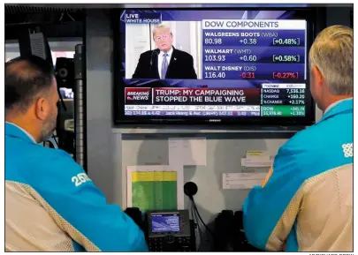  ?? AP/RICHARD DREW ?? Specialist­s on the floor of the New York Stock Exchange watch President Donald Trump’s news conference Wednesday. Major U.S. stock indexes soared Wednesday.