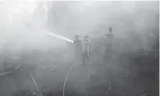  ?? AP/FILE ?? In a 2014 photo, firemen spray water on bush fires Riau province, Indonesia. in Siak