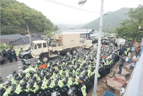  ??  ?? Protesters and police stand by as trailers carrying US’ THAAD missile defence equipment enter a deployment site in Seongju. — AFP photo