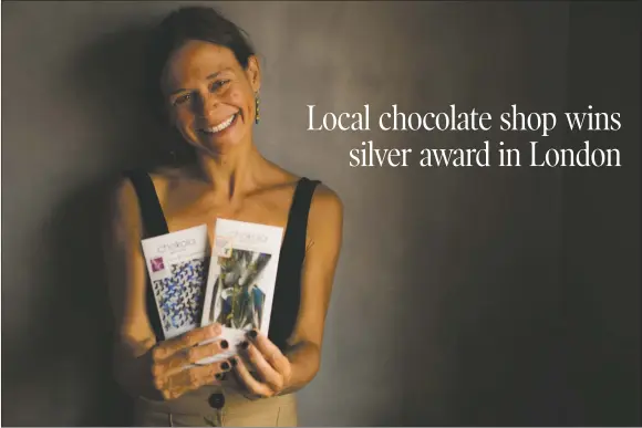  ?? NATHAN BURTON/Taos News ?? Debi Vincent, co-owner of Chokolá Bean to Bar, stands for a portrait while holding two of her award-winning chocolates on Saturday (Aug. 7).