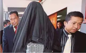  ??  ?? One of the prison warders charged with corruption being escorted to the Sessions Court in Kota Baru yesterday.
