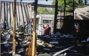  ?? ?? Silver, left, and Miller look over the remains of their home that caught fire on March 13.