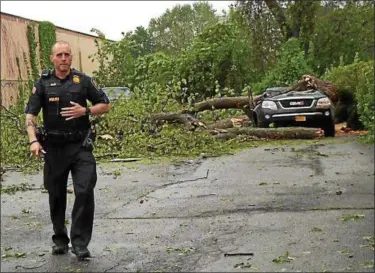  ?? PHOTO BY MARK LIEB ?? A police officer walks away from the scene in the city of Newburgh where an 11-year-girl was killed Tuesday afternoon by a tree that fell on the vehicle she was in.