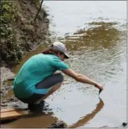  ?? MICHILEA PATTERSON — FOR MEDIANEWS GROUP ?? A woman retrieves a sample of the Schuylkill River in Douglassvi­lle as part of a water quality activity during a special Pedal & Paddle excursion organized by the Schuylkill River Greenways National Heritage Area.