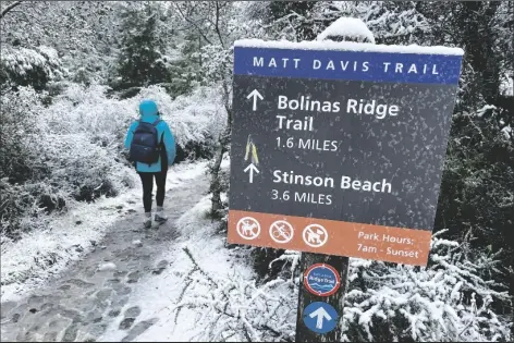  ?? HAVEN DALEY/ AP ?? A PERSON WALKS UP A TRAIL AT SNOW-COVERED MOUNT TAMALPAIS STATE PARK in Mill Valley, Calif., on Frida. California and other parts of the West are facing heavy snow and rain from the latest winter storm to pound the United States. The National Weather Service has issued blizzard warnings for the Sierra Nevada and Southern California mountains.
