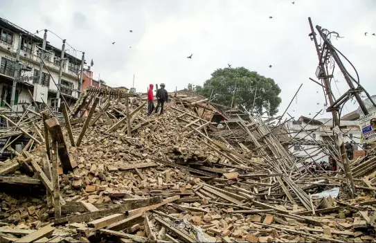  ?? Omar Havana/Getty Images ?? People stand on top of debris from a collapsed building Saturday at Basantapur Durbar Square in Kathmandu, Nepal, following a 7.8magnitude earthquake.