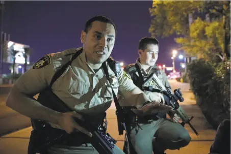  ?? John Locher / Associated Press ?? Police officers urge people to take cover near the location of the mass shooting that killed and injured people in Las Vegas.