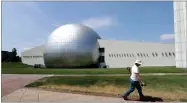  ?? AP PHOTO BY STEVEN SENNE ?? A worker carries a shovel in front of the Naismith Memorial Basketball Hall of Fame in Springfiel­d, Mass., Tuesday, June 23. The museum is scheduled to reopen in the beginning of July 2020 with a whole new look after a $22 million renovation.