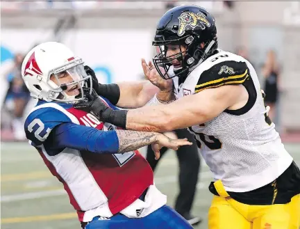  ?? PAUL CHIASSON/THE CANADIAN PRESS ?? Alouettes quarterbac­k Johnny Manziel is hit by Tiger-Cats’ Jason Neill during last week’s game at Molson Stadium. Manziel was frequently running for his life behind the Als’ porous offensive line during the game.