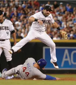  ?? (Reuters) ?? ARIZONA DIAMONDBAC­KS outfielder Daniel Descalso jumps over Chicago Cubs infielder Anthony Rizzo (44) to turn the double play in the seventh inning at Chase Field on Friday.