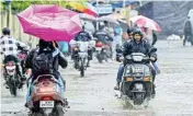  ??  ?? People make their way through a waterlogge­d street after heavy rains, at Sion in Mumbai on Saturday