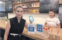  ??  ?? A model displays the Alipay payment applicatio­n at a True Money outlet in Bangkok.