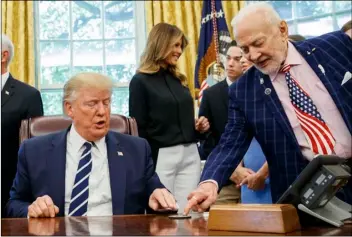  ??  ?? president Donald trump receives a gift from Apollo 11 astronaut buzz Aldrin, with first lady melania trump, during a photo opportunit­y commemorat­ing the 50th anniversar­y of the Apollo 11 moon landing in the oval office of the White House, on friday, in Washington. AP PhOTO/ALEx BrAndOn