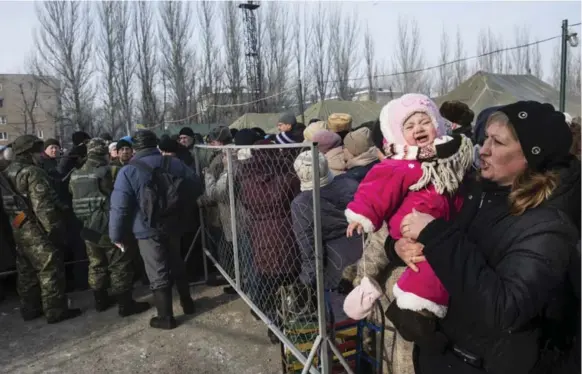  ?? EVGENIY MALOLETKA/THE ASSOCIATED PRESS ?? A baby girl cries in her mother’s arms as they stand in line to get humanitari­an aid. Ukraine’s conflict with Russia-backed rebels has intensifie­d, causing hardships for much of the population.