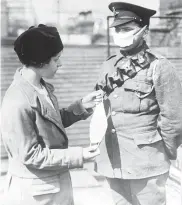  ??  ?? A nurse demonstrat­es a facemask on a British soldier during the influenza epidemic