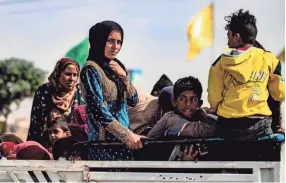  ?? DELIL SOULEIMAN, AFP/GETTY IMAGES ?? Displaced Syrians sit in the back of a pick up truck as Arab and Kurdish civilians flee amid Turkey's military assault on Kurdish-controlled areas in northeaste­rn Syria, on Oct.11 in the town of Tal Tamr.