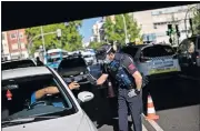  ?? [BERNAT ARMANGUE/ THE ASSOCIATED PRESS] ?? A police officer stops a vehicle Monday at a checkpoint in Madrid, Spain.