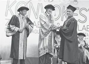  ??  ?? MASIDI (tengah) menyampaik­an sijil kepada salah seorang graduan pada konvokesye­n berkenaan.