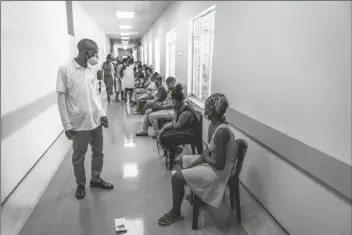  ?? SHIRAAZ MOHAMED/AP ?? A HOSPITAL WORKER ENSURES PEOPLE PRACTICE social distancing as they wait in line to get vaccinated against COVID-19 at the Lenasia South Hospital, near Johannesbu­rg, South Africa Wednesday.