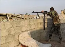  ??  ?? A Kurdish Peshmerga fighter stationed on the roof of a house in Bartella, a village recently recaptured from Isis