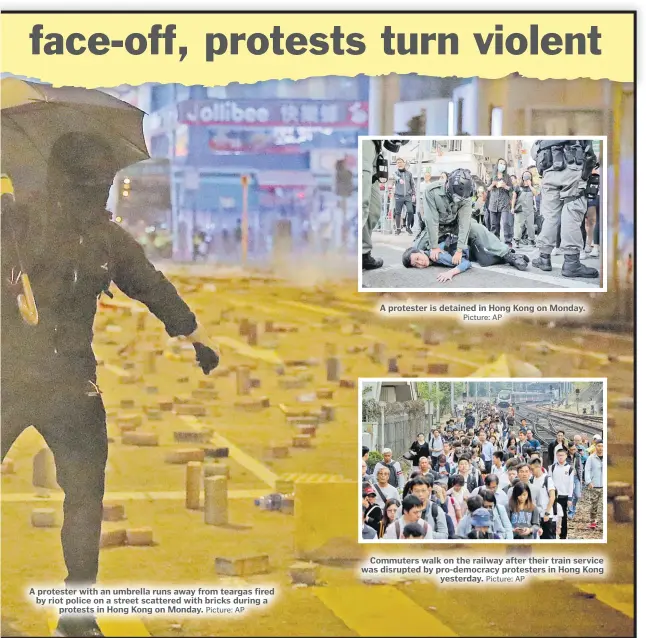  ?? Picture: AP Picture: AP Picture: AP ?? A protester with an umbrella runs away from teargas fired by riot police on a street scattered with bricks during a protests in Hong Kong on Monday.
A protester is detained in Hong Kong on Monday.
Commuters walk on the railway after their train service was disrupted by pro-democracy protesters in Hong Kong yesterday.