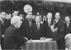  ??  ?? Lee (seated right) signs a document as witness of the installati­on ceremony. Looking on is Soo (seated left) and the committee members