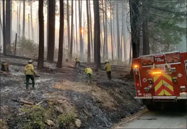  ?? CONTRIBUTE­D PHOTO ?? Part of the crew working the fire being brought to the road. Notice in this spot, the grass has been burned all the way to the edge of the asphalt. Still-burning chunks of wood are often turned over and allowed to be consumed.