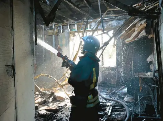  ?? ALEXEI ALEXANDROV/AP ?? A firefighte­r works at the scene of a reported artillery strike in Donetsk in occupied eastern Ukraine.