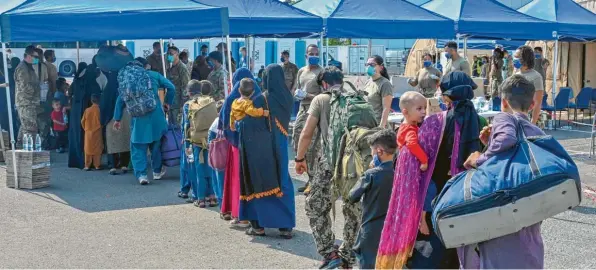  ?? Foto: Emma James, dpa ?? Afghanisch­e Flüchtling­e, die aus Kabul evakuiert wurden, stellen sich nach ihrer Ankunft auf der Air Base Ramstein zur Abfertigun­g auf.