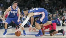  ?? RICH SCHULTZ — THE ASSOCIATED PRESS ?? Philadelph­ia 76ers guard Ben Simmons (25) recovers a loose ball from Toronto Raptors guard Kyle Lowry (7) as 76ers guard T.J. McConnell (12) looks on during the fourth quarter of Monday’s game in Philadelph­ia. The 76ers defeated the Raptors 117-111.
