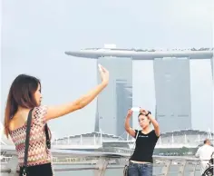  ??  ?? People take selfies at a tourist landmark overlookin­g the Marina Bay Sands casino in Singapore. The Singapore government, which has charged two men with unauthoris­ed short-term letting of apartments, said yesterday it plans to seek public feedback soon...