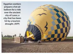  ??  ?? Egyptian workers prepare a hot air balloon for a ride over the ancient city of Luxor, a city that has been hit by a tourism drought. (AFP)